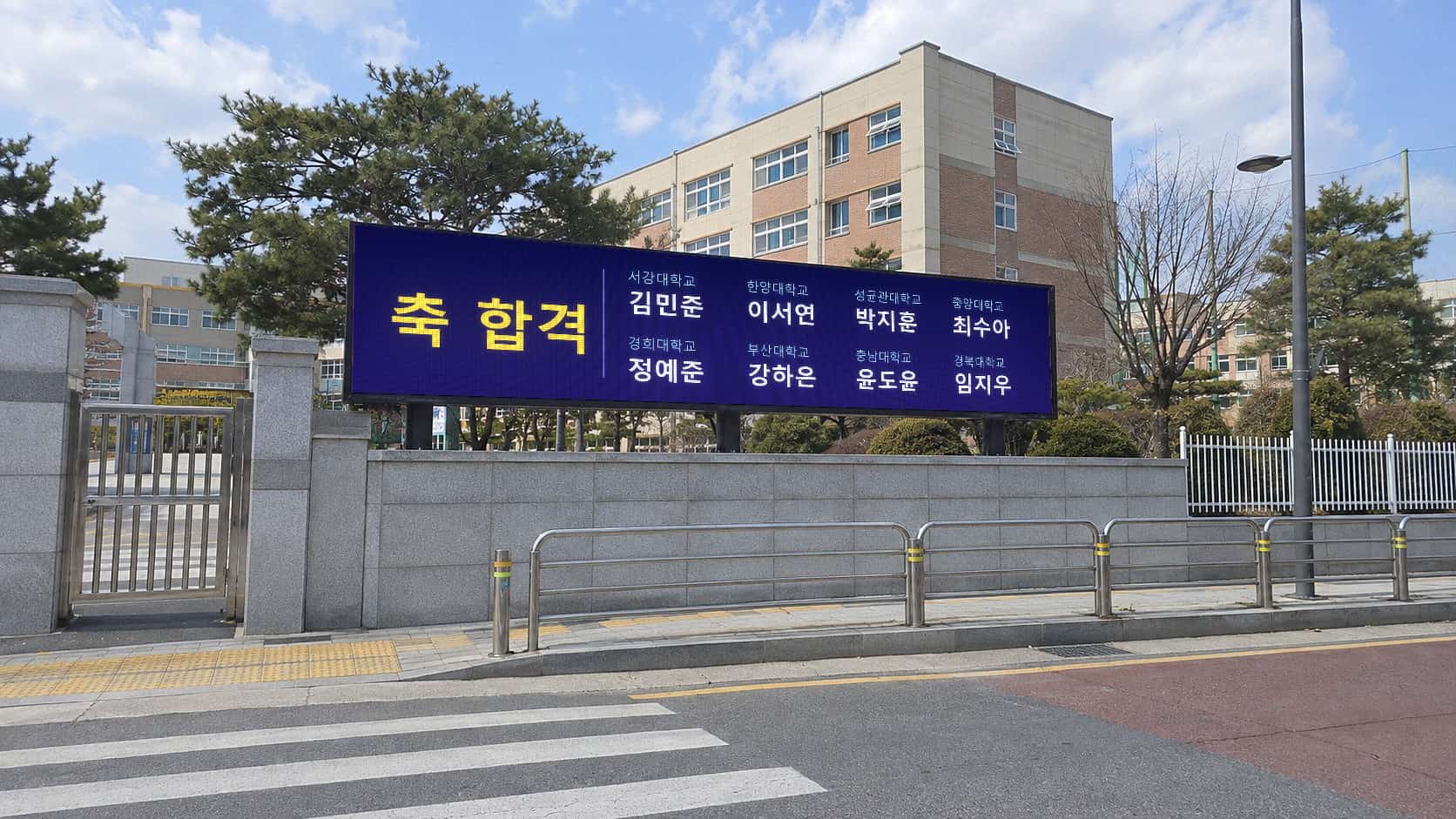 고등학교 정문 옆 담장 위 LED 전광판에 축 합격 문구와 졸업생 이름·합격 대학 명단이 표시된 모습