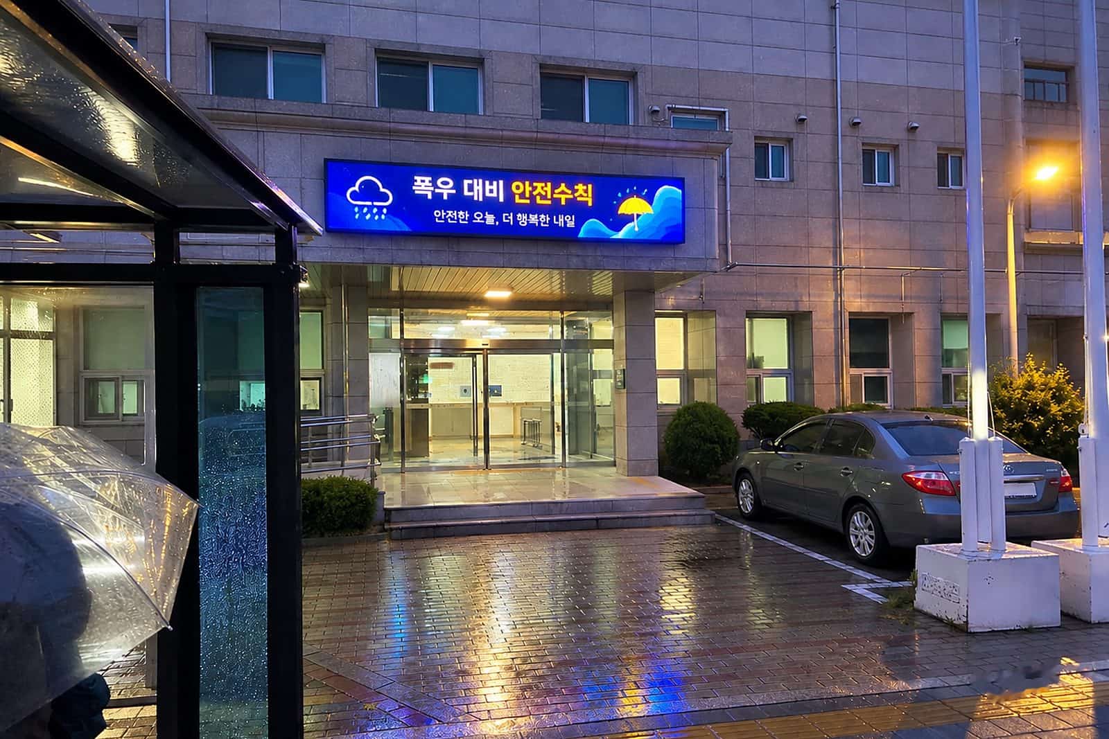 비 내리는 밤 건물 외벽 LED 전광판(전자현수막)에 폭우 대비 안전수칙이 표시된 장면