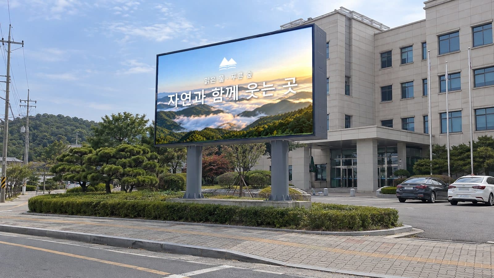 청사 앞 도로변 화단에 기둥 두 개로 세운 옥외 LED 전광판에 맑은 물 푸른 숲 자연과 함께 웃는 곳 슬로건 화면