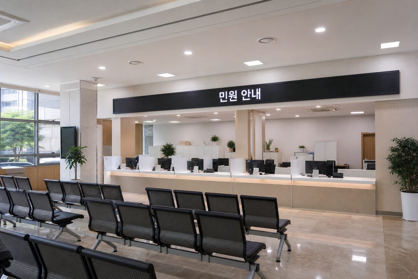 한국 관공서 민원실 창구 위에 설치된 가로형 LED 화면에 "민원 안내" 문구가 표시되어 있다