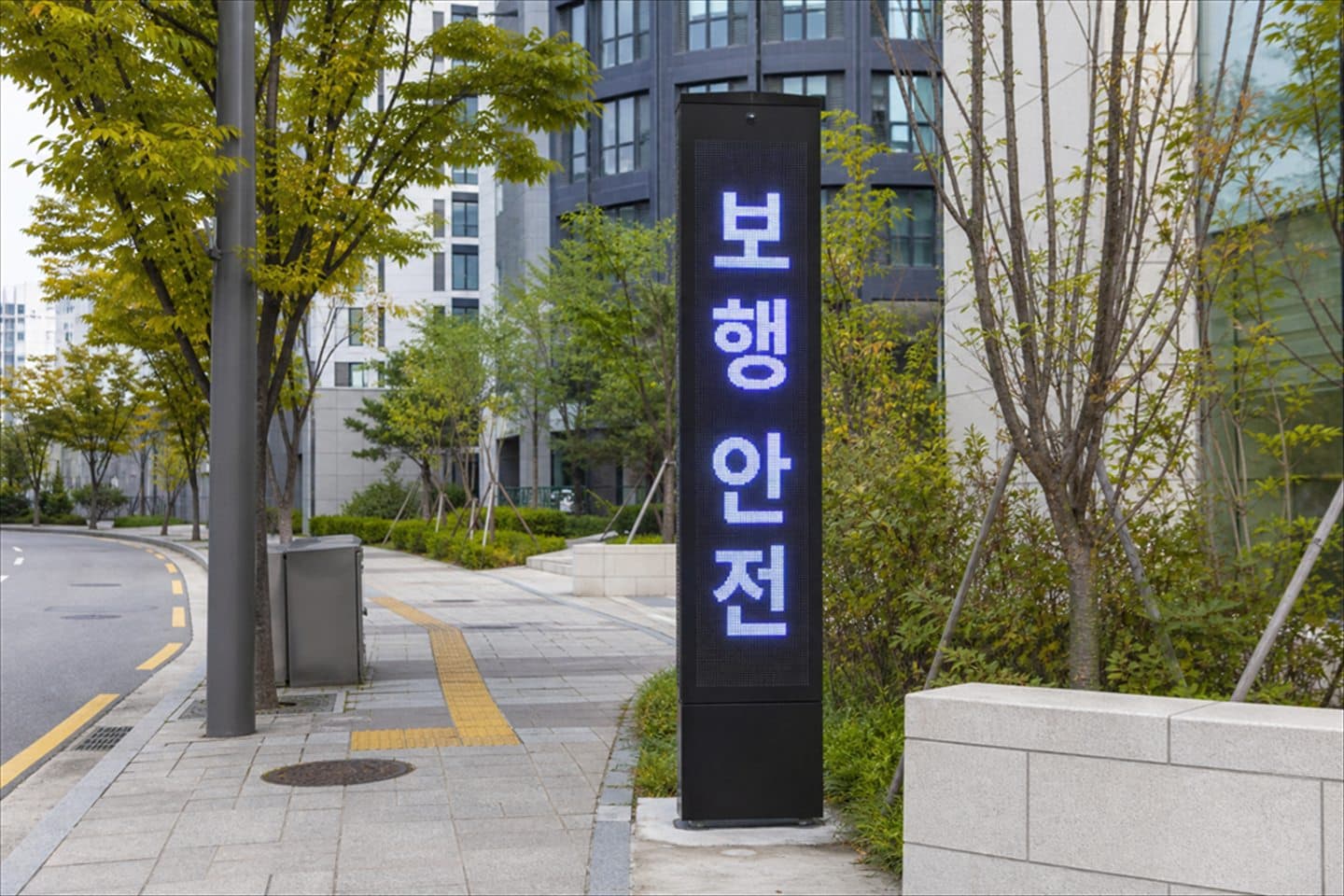 한국 아파트 단지 보행로에 세워진 세로형 LED 지주가 보행 안전 문구를 표시하고 있다