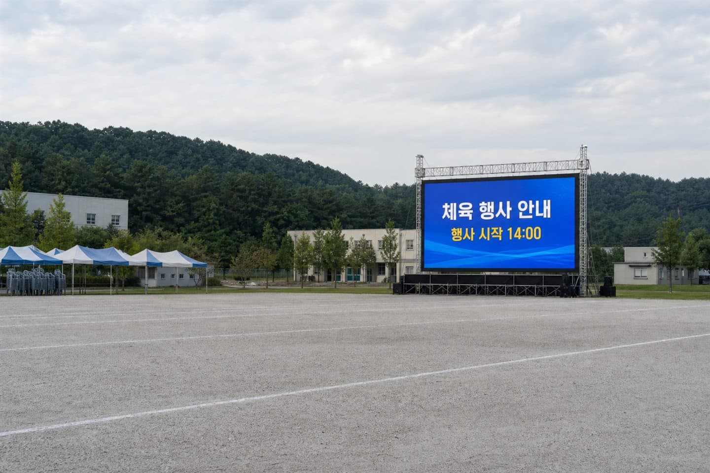 학교 운동장 건너편에 설치된 대형 화면이 체육 행사 안내와 시작 시각을 표시하고 있다