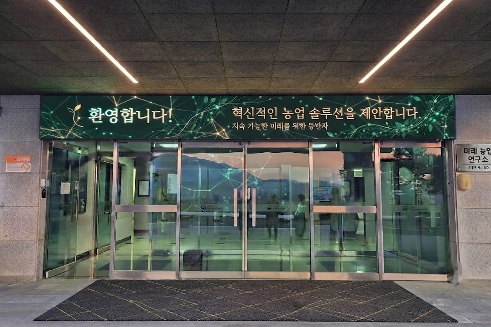 건물 현관 위 전자현수막에 환영 문구가 표시된 장면