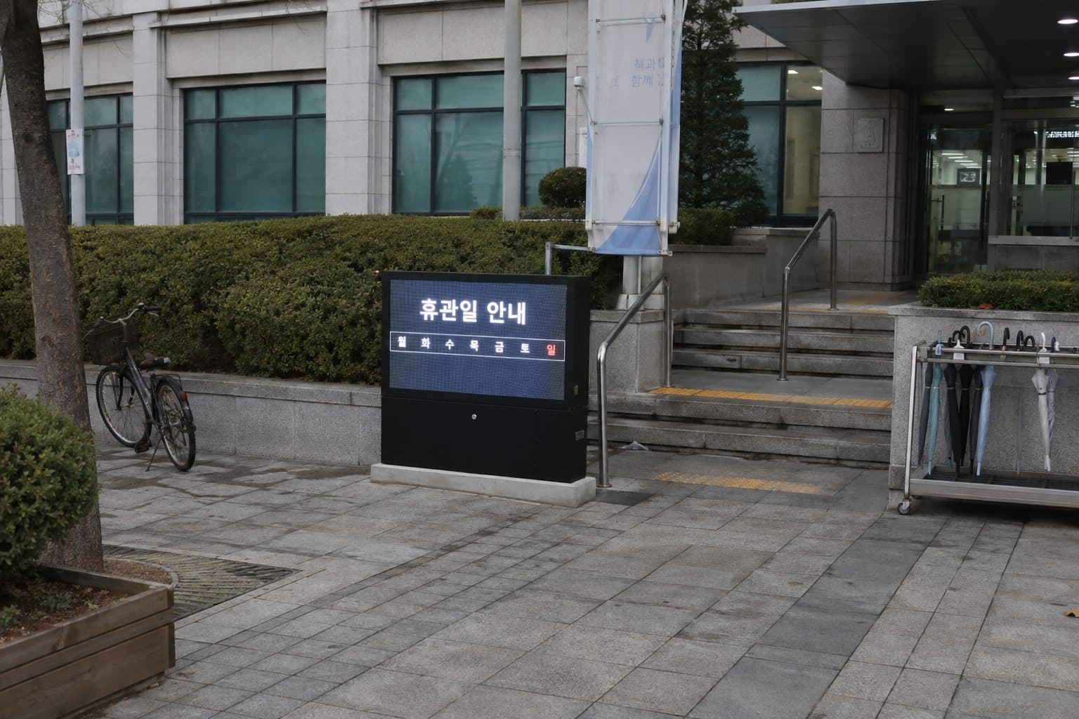한국 공공 도서관 로비 벽면의 세로형 이용·운영시간·시설 안내 화면
