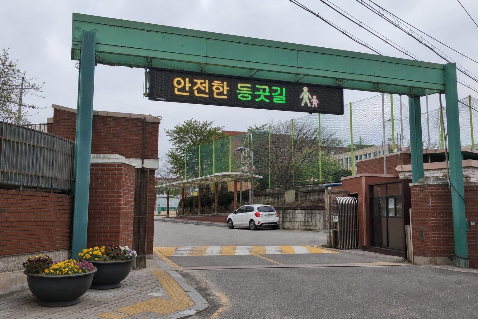 밝은 낮 한국 학교 정문 위에 설치된 등굣길 안전 안내 전자현수막