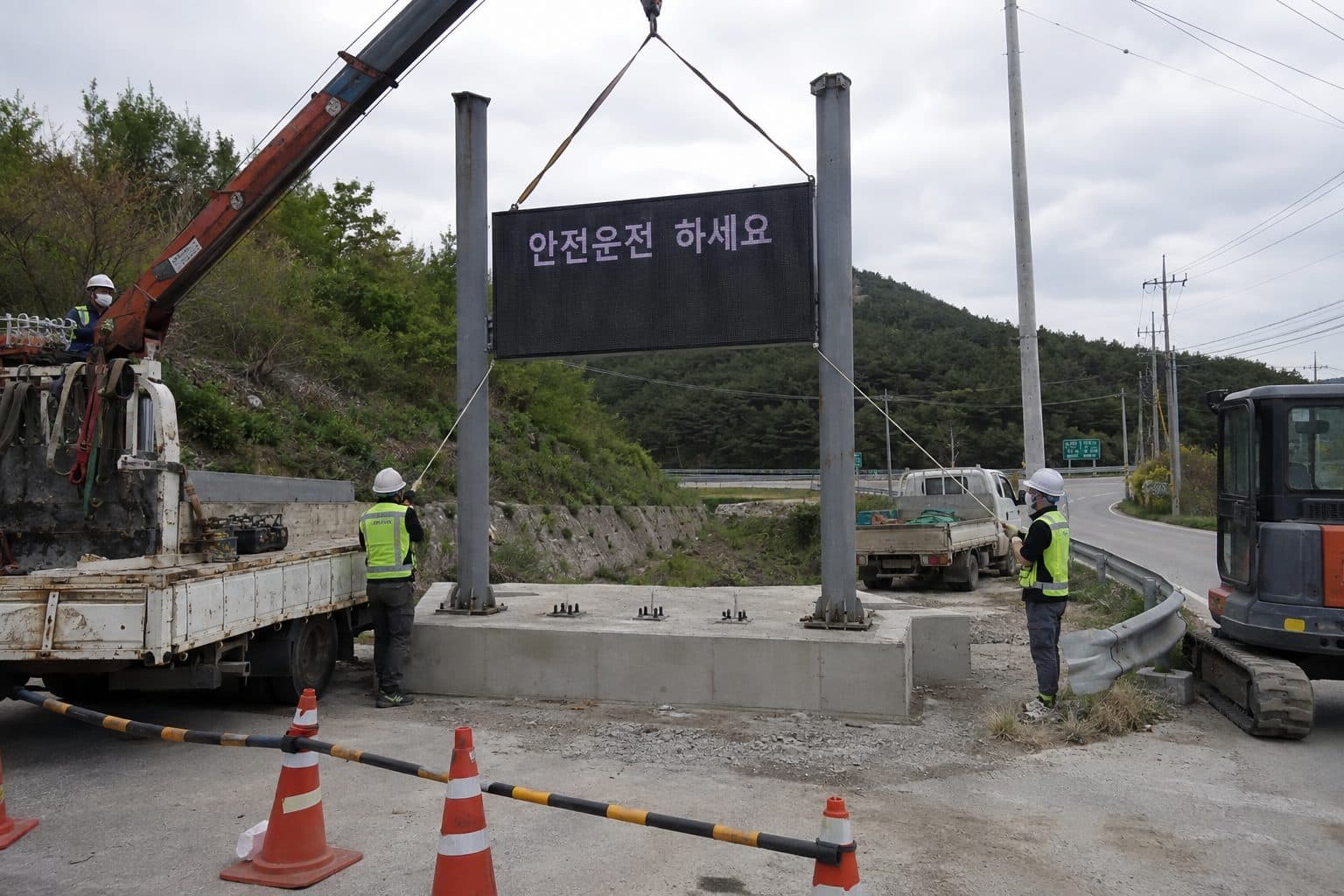 도로변 H빔 지주에 카고크레인으로 전광판 본체를 올려 고정하는 시공 현장