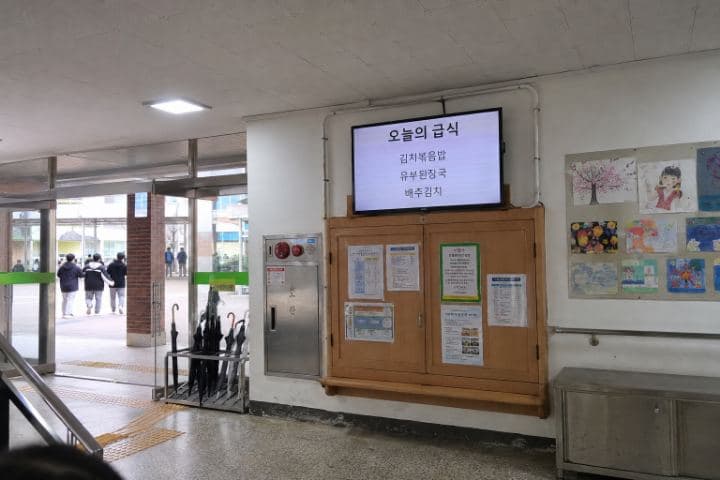학교 현관 게시판 옆 벽면에 설치된 화면이 그날의 급식 메뉴를 표시하고 있다