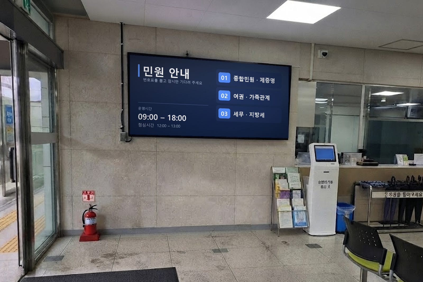 민원실 벽면 화면에 창구별 안내와 운영시간이 표시된 장면