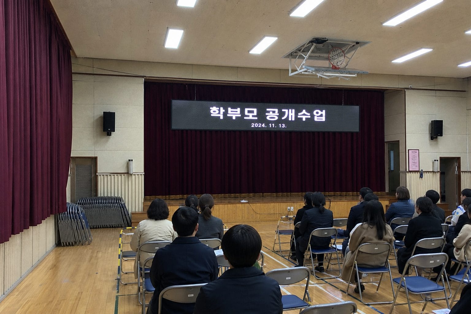 학교 강당 무대 앞 가로형 화면에 학부모 공개수업 안내