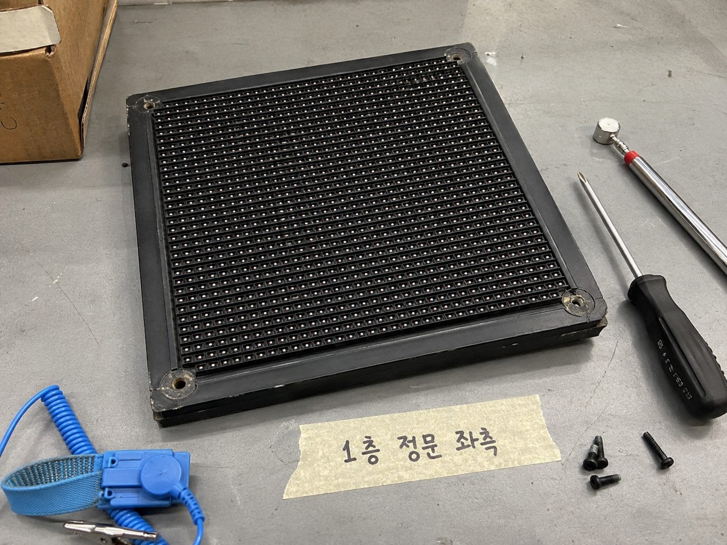작업대 위에 놓인 LED 모듈 한 장과 교체용 공구, 설치 위치를 적은 손글씨 라벨