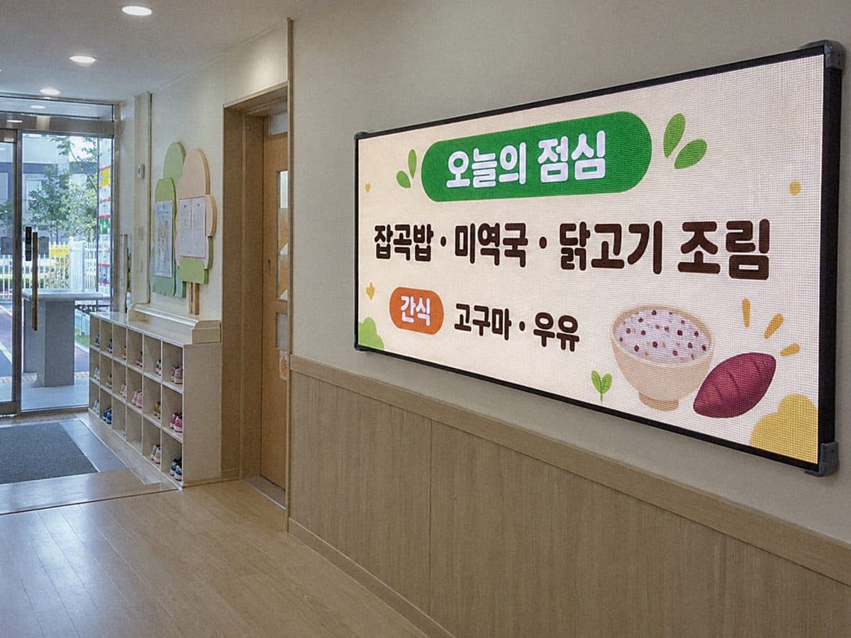 어린이집 현관 안 신발장 옆 벽에 단 실내 LED 화면에 오늘 점심과 간식 식단이 나오는 장면